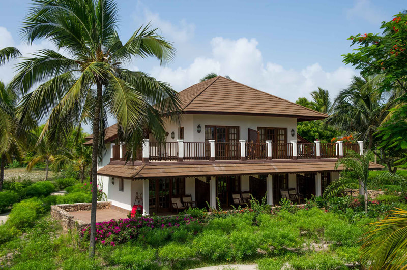 Ein Haus im Kolonialstil umgeben von einem Garten und Palmen