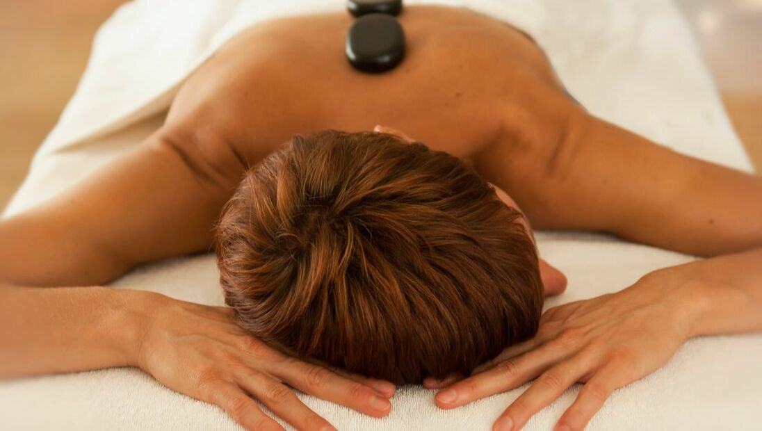 Eine Frau auf einer Massageliege mit heißen Steinen auf dem Rücken