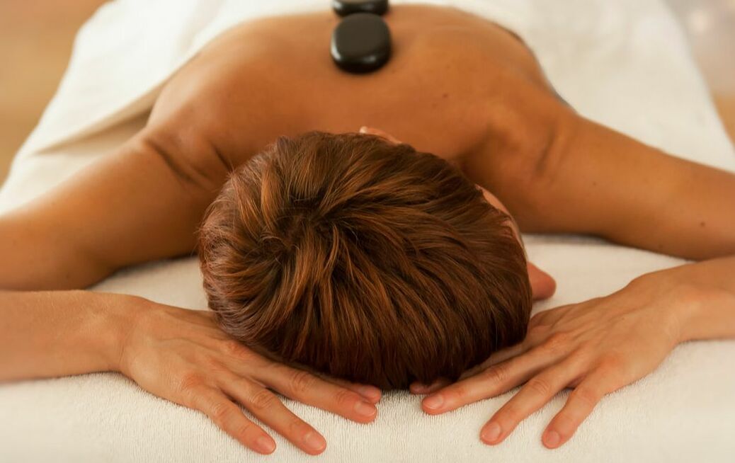 Eine Frau bei einer Massage die heiße Steine auf dem Rücken hat