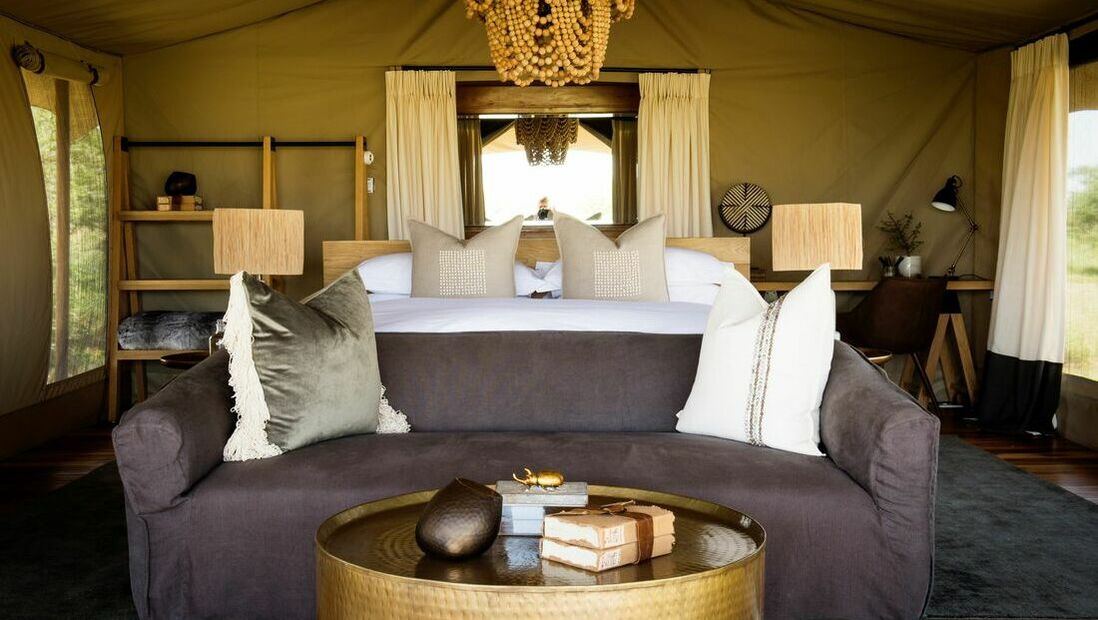 Ein goldener Tisch neben einem Sofa und einem Doppelbett in einem Zelt
