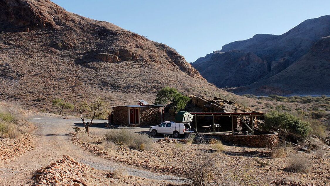 Ein Camper steht neben einem Campingplatz in einer steinernen Wüstenlandschaft