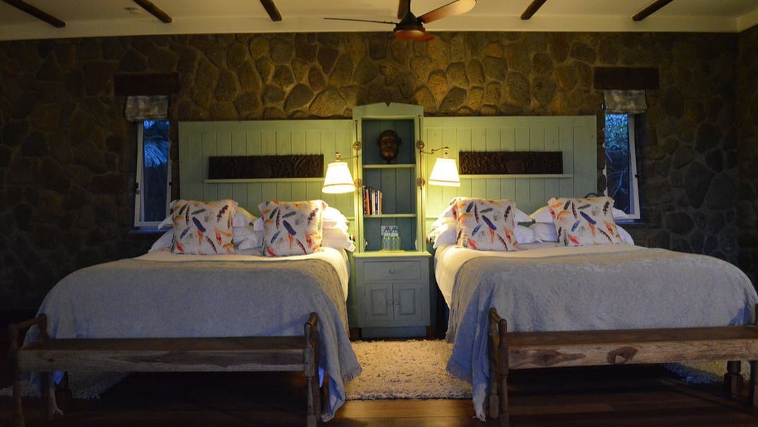 Zwei hölzerne Doppelbetten mit bunten Kopfkissen in einem Schlafzimmer