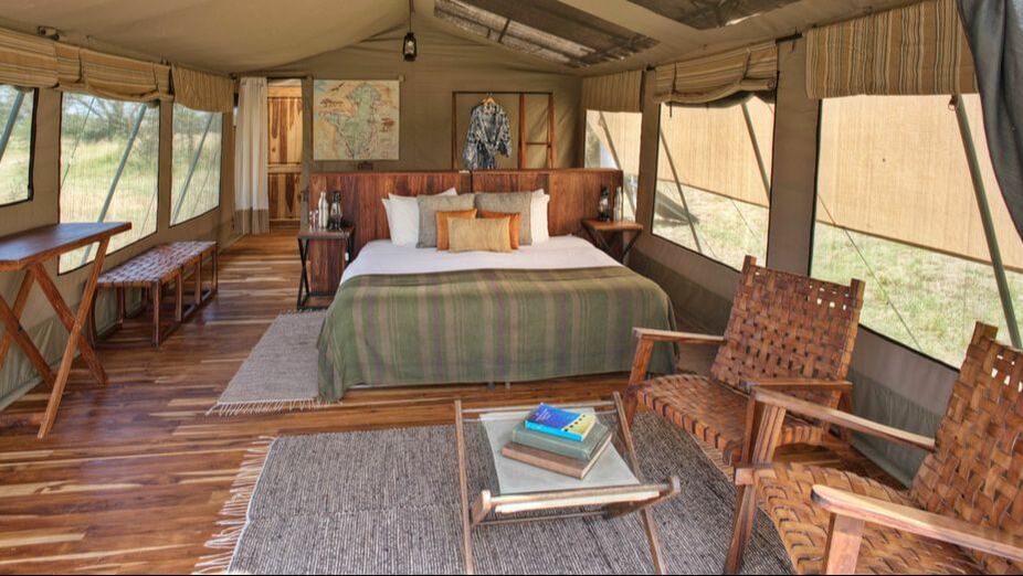 Ein großes Doppelbett in einer Zelt-Lodge mit Parkettboden