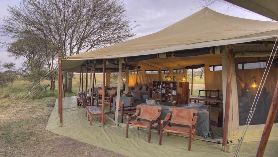 Ein großes Zelt mit vielen Stühlen in der Savanne von Tansania
