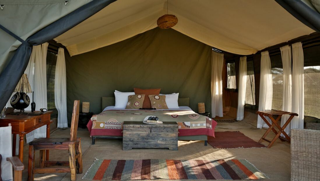 Ein gemütliches Doppelbett mit bunter Bettwäsche in einem Zelt