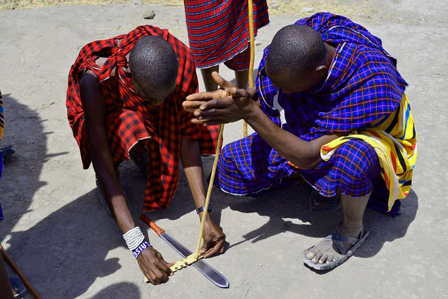 Traditionelle Massai beim Schärfen eines Messers