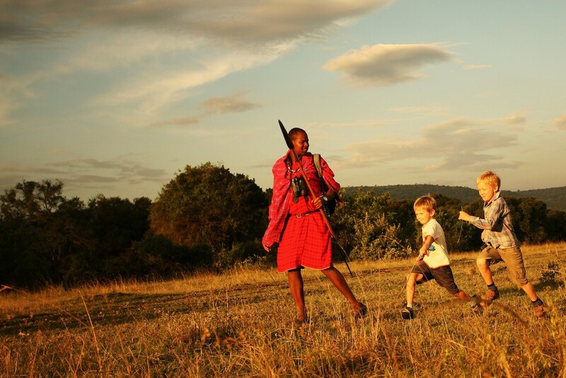 Massai wandert mit Kindern durch die Steppe