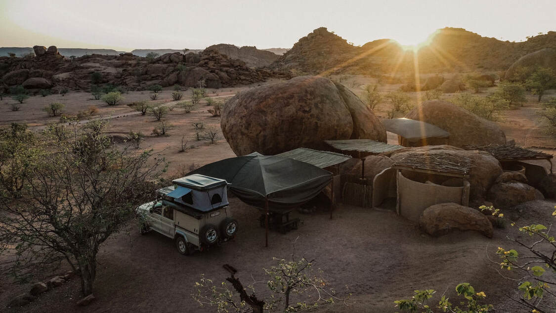 Ein Safarifahrzeug steht neben einem großen Felsen in Afrika
