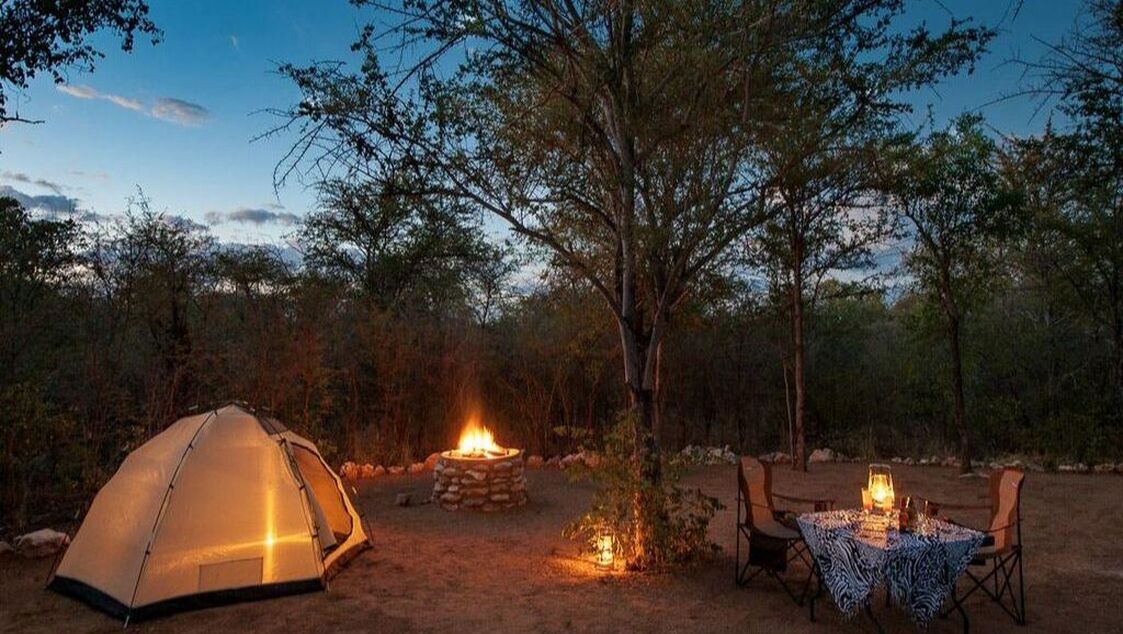 Ein Zelt und ein Lagerfeuer in der Abenddämmerung im Etosha Nationalpark